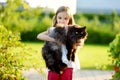 Cute little girl holding giant black cat