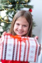 Cute little girl holding gift box at home near Christmas tree. DIY present, holiday concept Royalty Free Stock Photo
