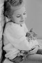 Cute little girl holding hands on the ginger kitten