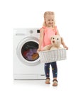 Cute little girl holding laundry basket with teddy bear near washing machine Royalty Free Stock Photo