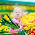 Cute little girl holding a leek in a food store Royalty Free Stock Photo