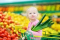 Cute little girl holding a leek in a food store Royalty Free Stock Photo