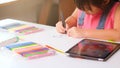 Cute little girl holding a magic pen drawing on paper with digital tablet and stationery on the table. Child using digital tablet Royalty Free Stock Photo