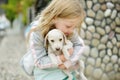 Cute little girl holding small white puppy outdoors. Kid playing with baby dog on summer day Royalty Free Stock Photo