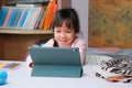 Cute little girl holding a Stylus pen working on a tablet. Child using digital tablet searching information on internet for her Royalty Free Stock Photo