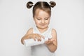 Cute little girl holding white plastic bottle in her hands, and pouring oil or cream milk, looking at the bottle. Baby Royalty Free Stock Photo