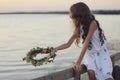 Cute little girl holding wreath made of beautiful flowers near river in evening Royalty Free Stock Photo