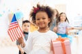 Cute little girl holds a gift and a flag of the USA at the celebration of her birthday. Royalty Free Stock Photo