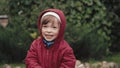 Cute little girl in a hooded jacket is happy and makes faces in front of camera Royalty Free Stock Photo