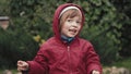 Cute little girl in a hooded jacket is happy and makes faces in front of camera Royalty Free Stock Photo