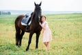 Cute little girl on a horse in a summer field dress. sunny day Royalty Free Stock Photo