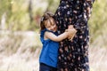 Cute little girl hugging and kissing her mother`s pregnant belly in spring nature Royalty Free Stock Photo