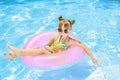 Cute little girl with inflatable ring drinking juice in swimming pool Royalty Free Stock Photo