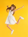 Cute little girl jumping on yellow background Royalty Free Stock Photo