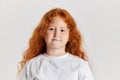 Cute little girl, kid with long curly red hair looking at camera isolated over white background. Concept of children Royalty Free Stock Photo