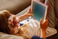 Cute girl kid using iPad digital computer tablet on bed for education or playing game.