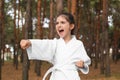 Cute little girl in kimono practicing karate in forest