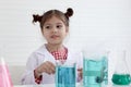 Cute little girl in lab coat doing science experiment at class room, young schoolgirl scientist kid having fun in chemistry