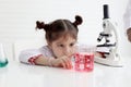 Cute little girl in lab coat doing science experiment at class room, young schoolgirl scientist kid having fun in chemistry