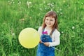 Cute little girl laughing and holding toy balloon in hand on the green meadow outdoor, happy childhood concept Royalty Free Stock Photo