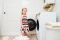 a cute little girl with laundry near the washing machine. Royalty Free Stock Photo