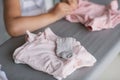Cute little girl is leaning on ironing clothes on board at home. Daughter helping to mother ironing clothes for baby Royalty Free Stock Photo