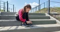 Cute little girl learning to tie shoelaces outdoors on summer day Royalty Free Stock Photo