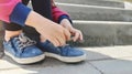 Cute little girl learning to tie shoelaces outdoors on summer day Royalty Free Stock Photo