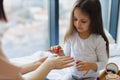 Cute little girl learns to paint her nails by applying polish on mother hands. Royalty Free Stock Photo