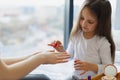 Cute little girl learns to paint her nails by applying polish on mother hands. Royalty Free Stock Photo