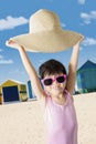 Cute little girl lifting her hat on the beach Royalty Free Stock Photo