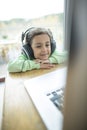 Cute little girl listening to music on headphones while using laptop at home Royalty Free Stock Photo