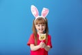 Cute little girl with lollipop and bunny ears on color background Royalty Free Stock Photo