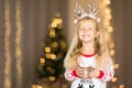 Cute Little girl with long blonde hair in christmas pajamas holding cup of cacao with marshmallow at home. Christmas decorations