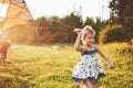 Cute little girl with long hair running with kite in the field on summer sunny day