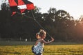 Cute little girl with long hair running with kite in the field on summer sunny day