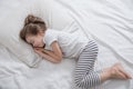 Cute little girl with long hair sleeping in bed