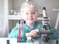 Cute little girl looking into microscope at his desk at home. Young scientist making experiments in his home laboratory Royalty Free Stock Photo