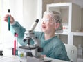 Cute little girl looking into microscope at his desk at home. Young scientist making experiments in his home laboratory Royalty Free Stock Photo