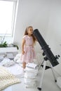 A cute little girl is looking at a telescope on an aluminum stargazing stand in a room Royalty Free Stock Photo