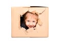 Cute little girl looks out of a torn hole in a box Royalty Free Stock Photo