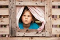 Cute little girl looks out window of wooden children's house. Holidays in village. Happy childhood. Royalty Free Stock Photo