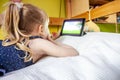 Cute little girl lying on bed and using her tablet computer Royalty Free Stock Photo