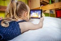 Cute little girl lying on bed and using her tablet computer Royalty Free Stock Photo