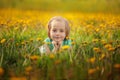 Cute little girl lying on the yellow dandelion meadow in summer day. Royalty Free Stock Photo