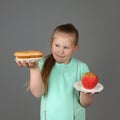 Cute little girl makes choice between hamburger and apple Royalty Free Stock Photo