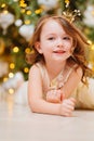 a cute little girl makes a wish and waits for Santa Claus under Christmas tree. Royalty Free Stock Photo