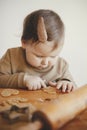 Cute little girl making christmas cookies on messy table, close up. Adorable toddler daughter helping mother and cutting dough for Royalty Free Stock Photo