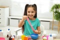 Cute little girl making DIY slime toy at table