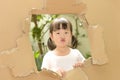 Cute little girl making funny faces in torn paper wall Royalty Free Stock Photo